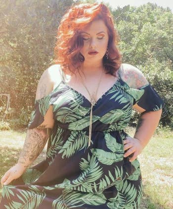 Reviewer wearing a black cold shoulder dress with green tropical leaves on it