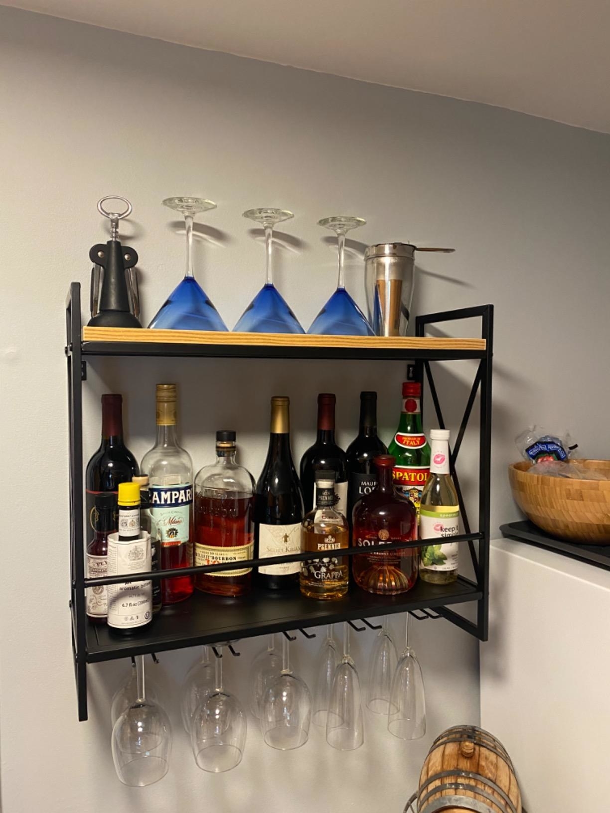 A reviewer photo of the wine rack, which has a flat shelf on top, a wine shelf with a safety bar in the middle, and a rack to hang wine glasses from on the bottom