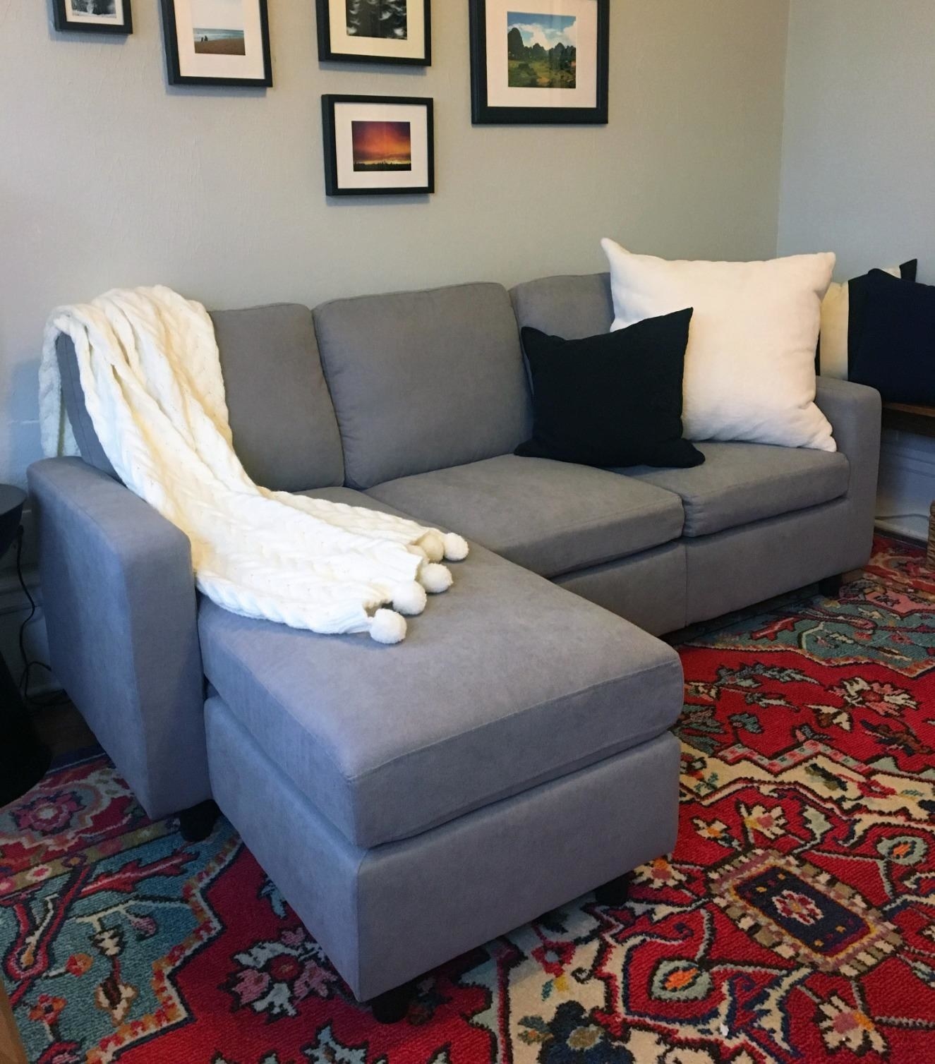 reviewer photo of a grey sectional couch in a living room with a white throw and pillows on top
