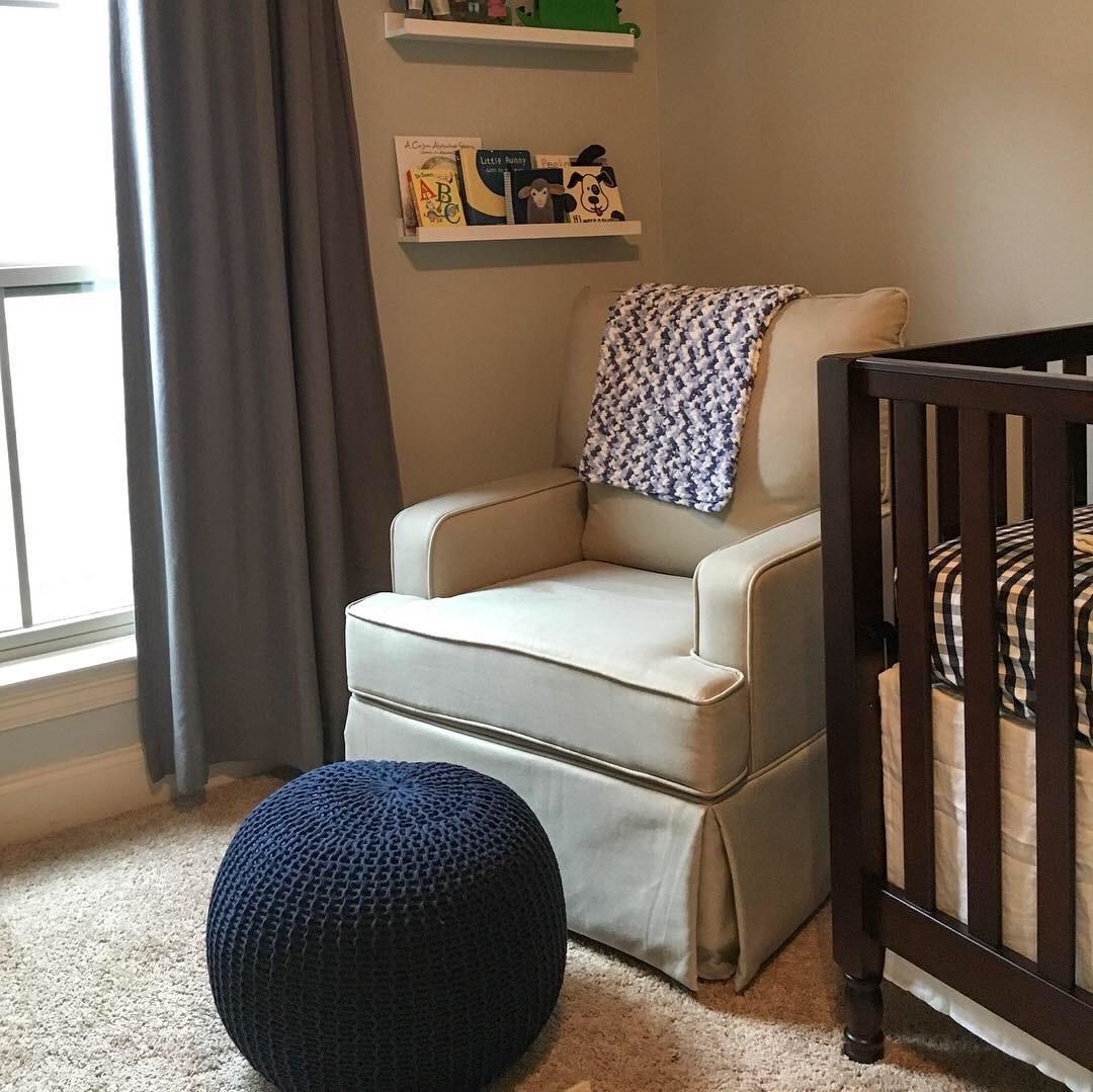 reviewer photo of a round indigo knit pouf next to an armchair