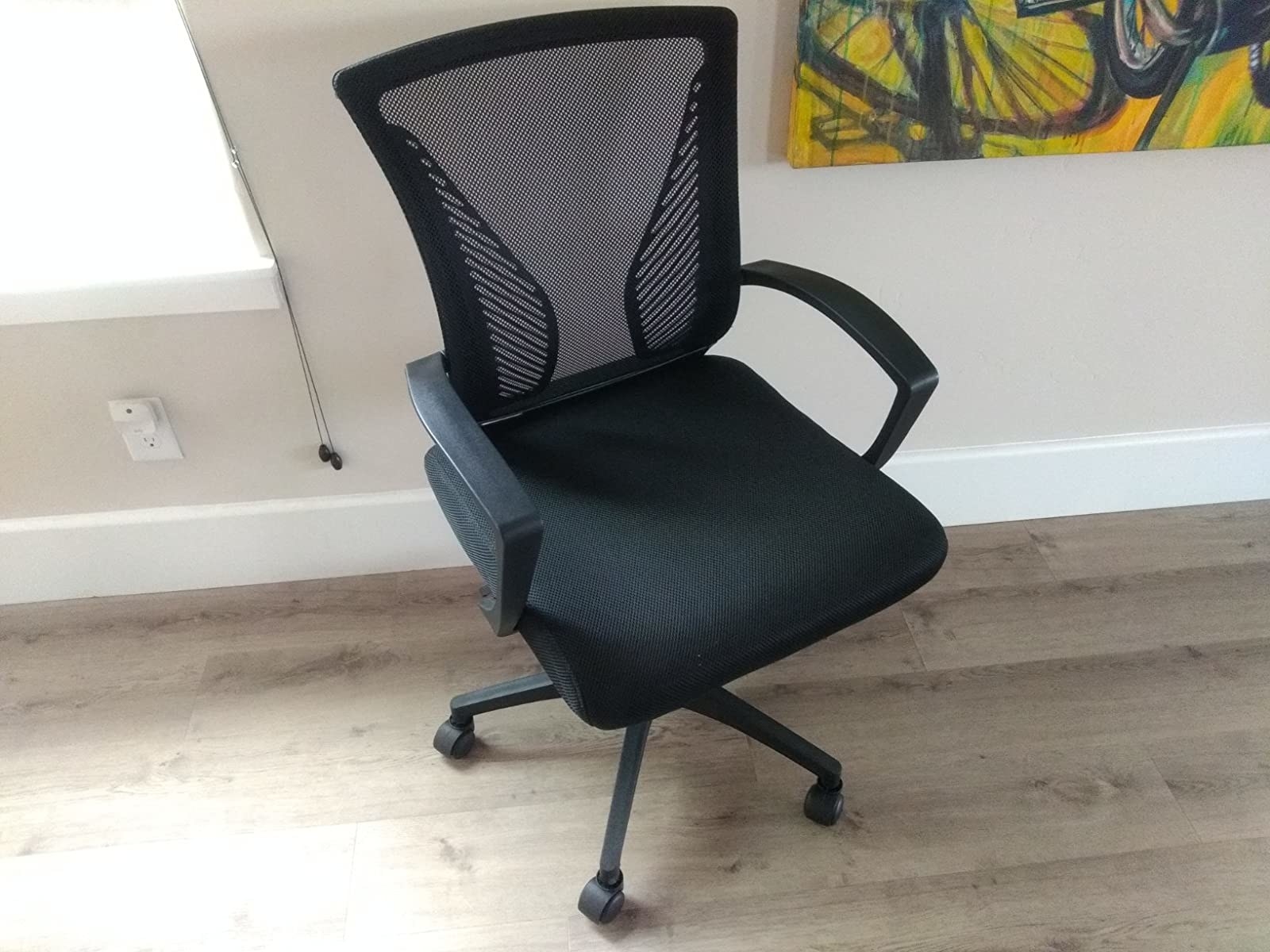 reviewer photo of a black office chair with mesh back, arm rests, and cushioned seat