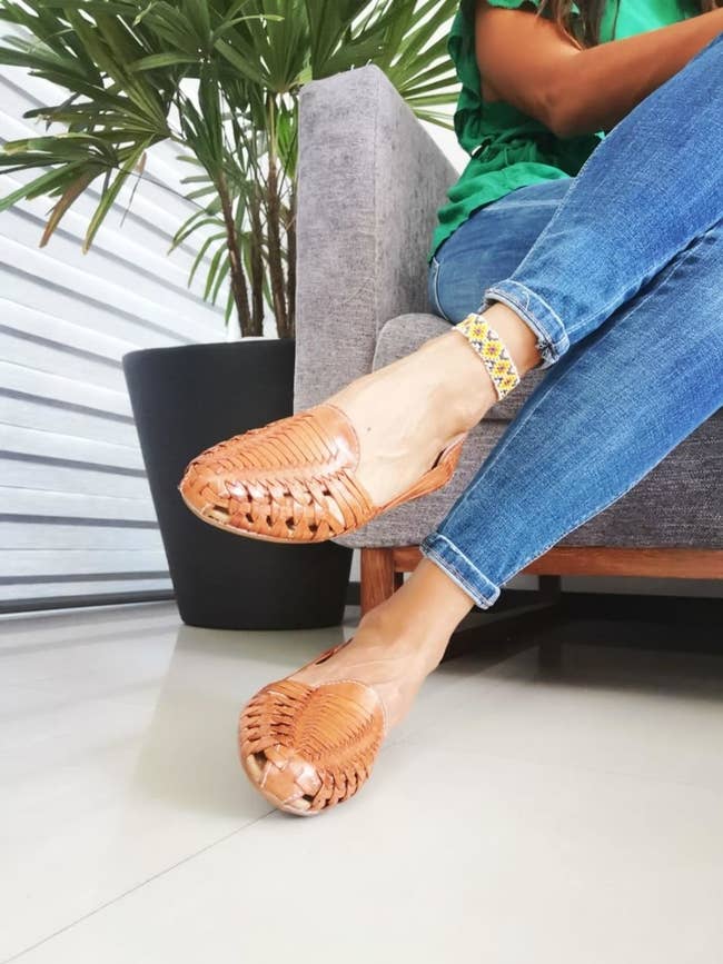 models feet in flat woven leather sandal/shoes with a light brown finish