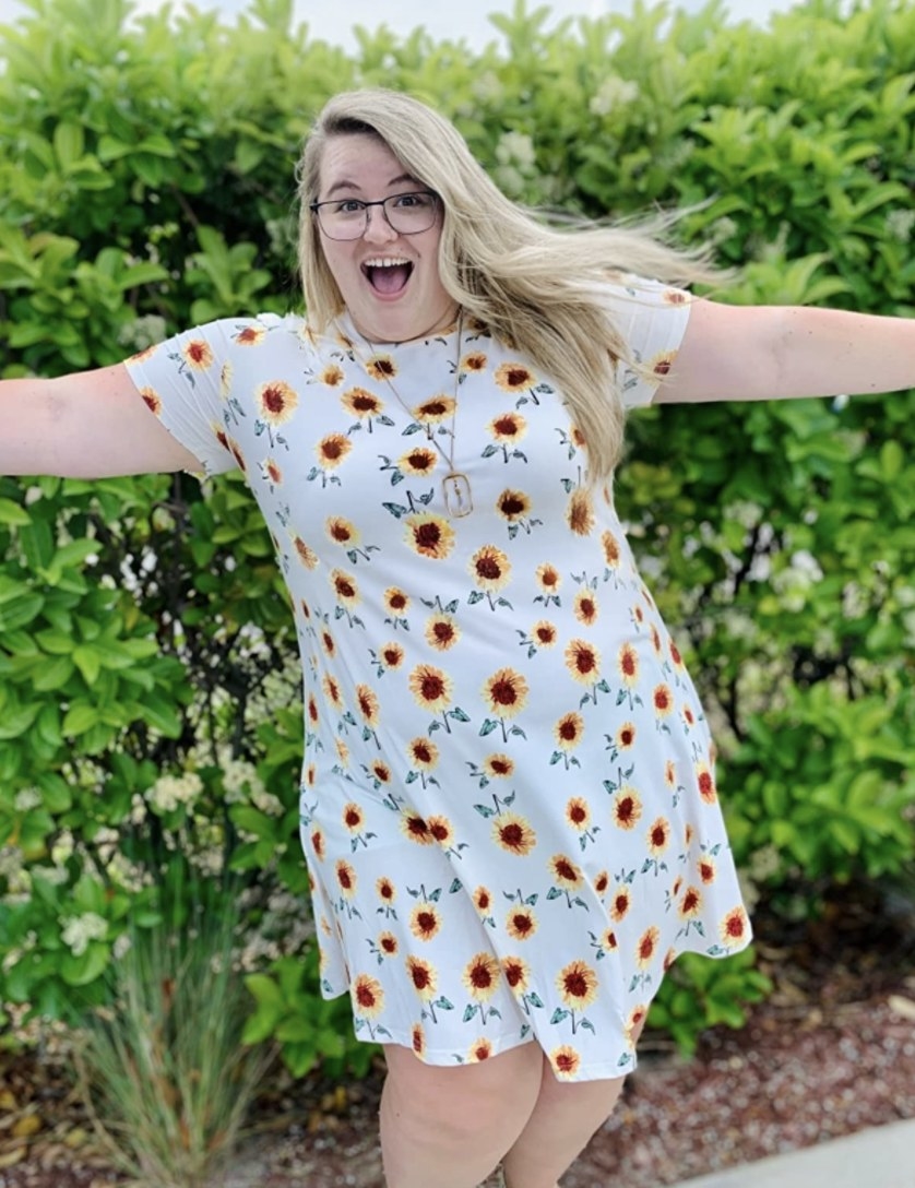 A person wearing a white dress with sunflowers on it
