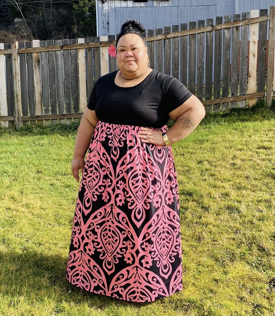 A person wearing a pink and black maxi dress with a geometric pattern on it