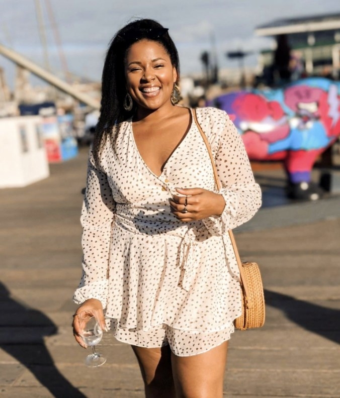 A person wearing a cream romper with black dots on it