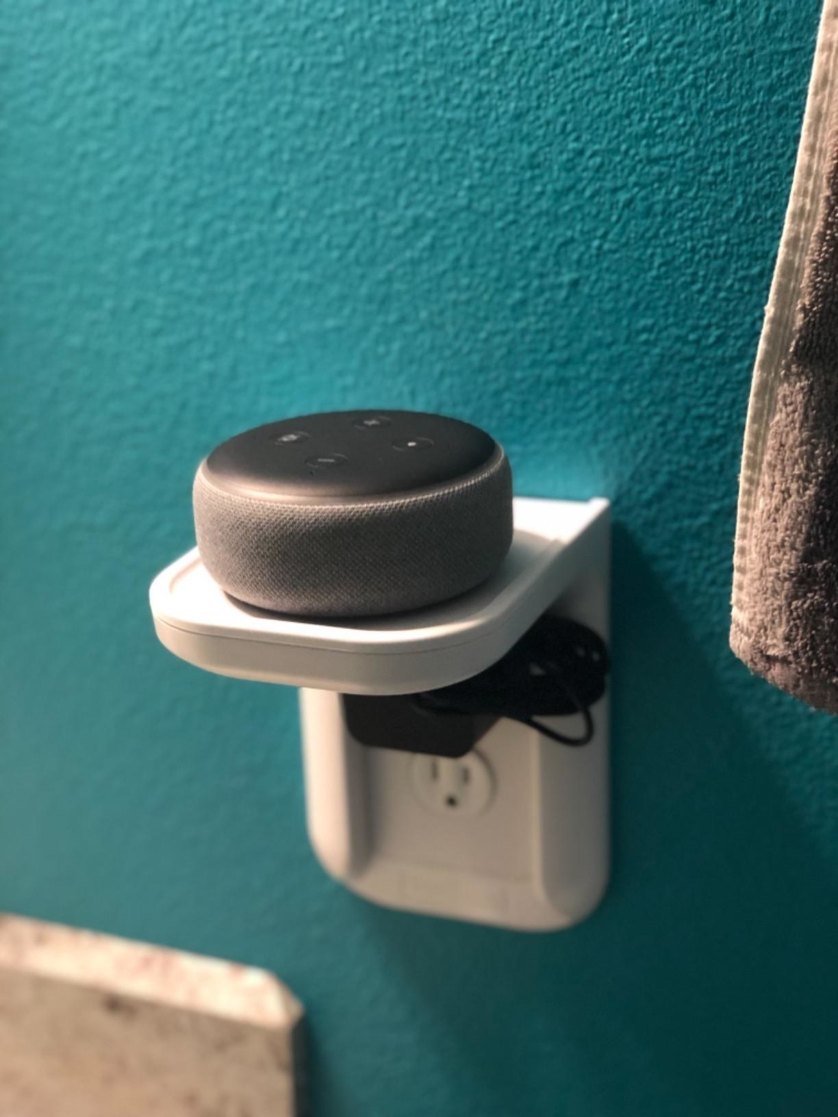 a reviewer photo of the alexa dot on top of the outlet shelf
