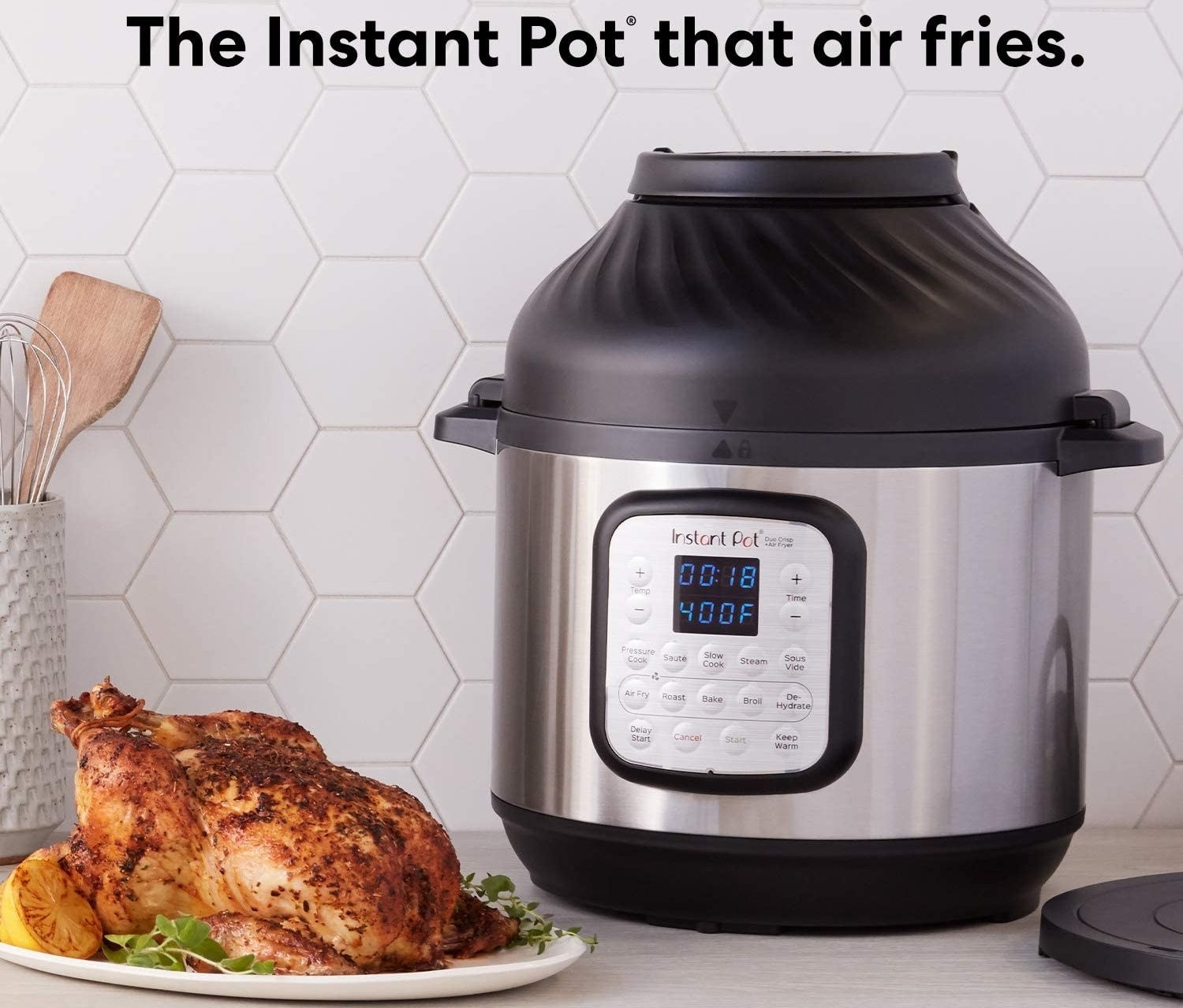 stainless steel instant pot with an air fryer attachment. fully roasted chicken next to it