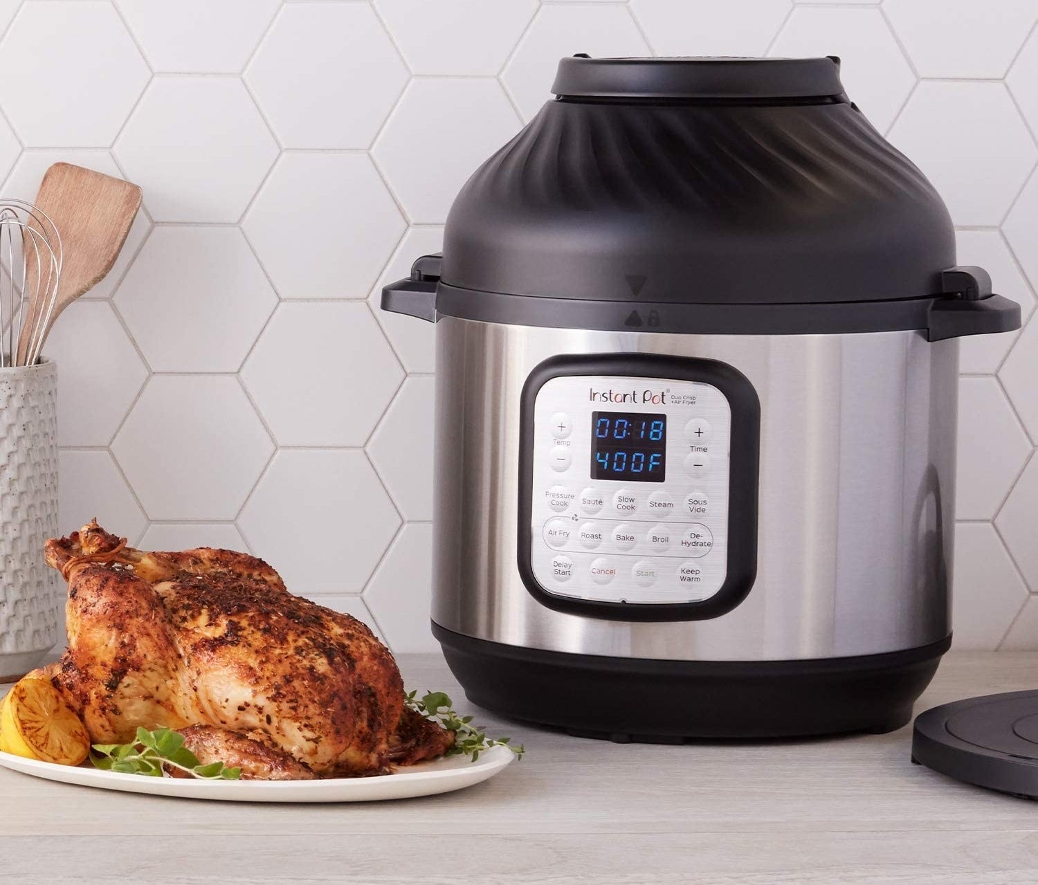 stainless steel instant pot with an air fryer attachment. fully roasted chicken next to it