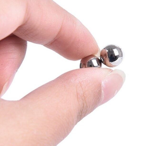 A person holding two magnetic balls between their fingers 