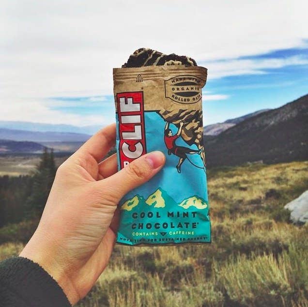 Cool mint chocolate Clif bar held in photographer&#x27;s hand against the view of mountains in the horizon