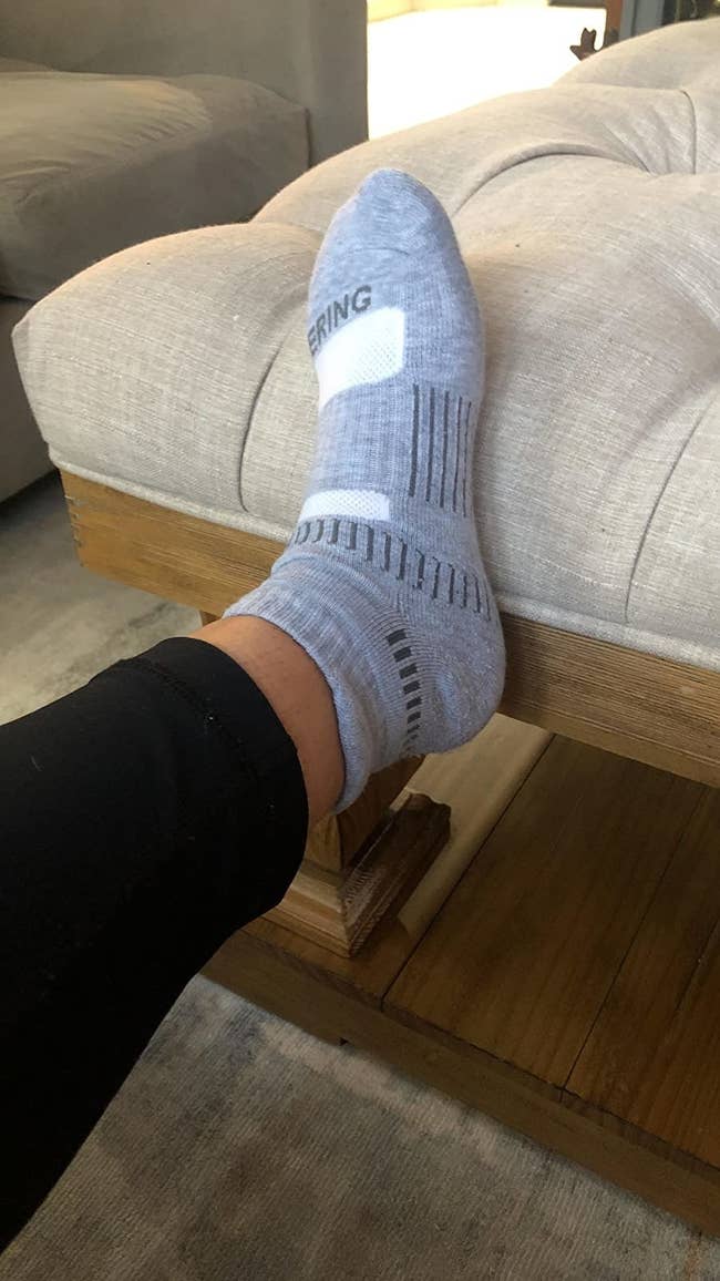 reviewer wearing one grey athletic sock with a tab on the ankle