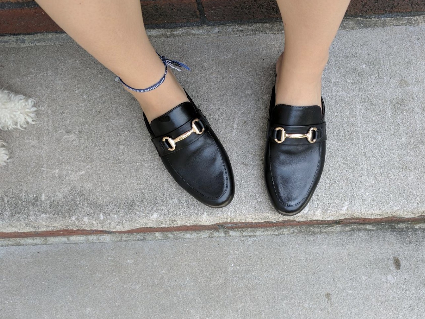 Black slip on loafers with a gold buckle on top