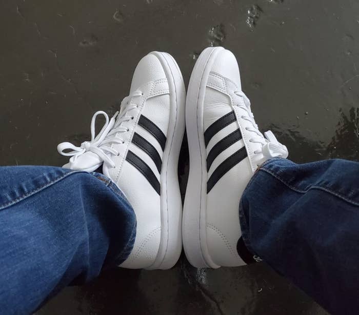 Reviewer photo of the white sneakers with three black stripes on the sides