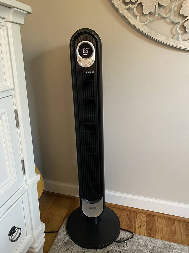 reviewer photo of a black standing tower fan that's plugged in to the wall