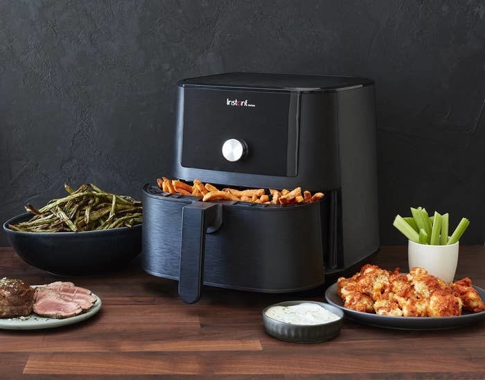 The air fryer filled with fries and surrounded by foods