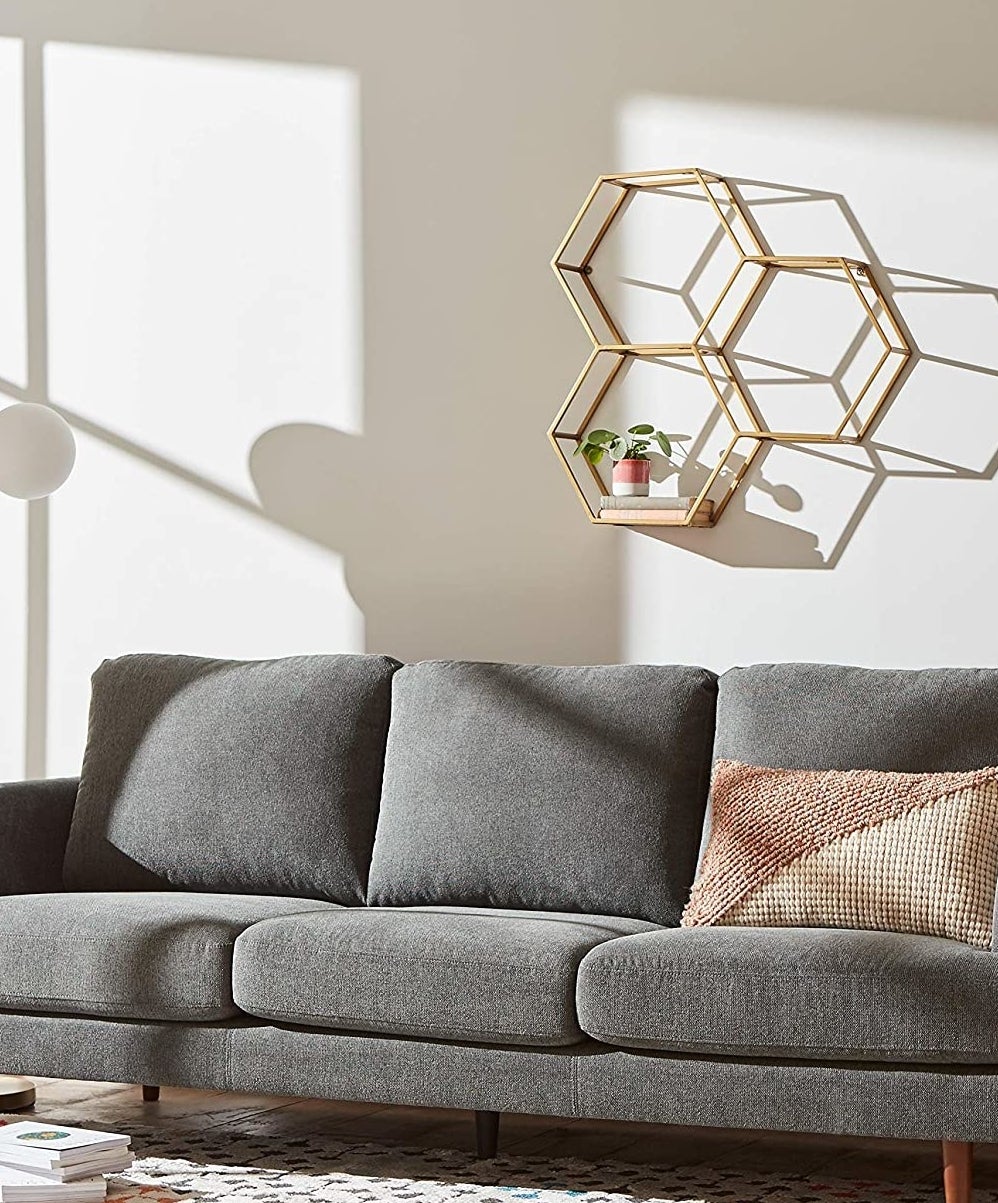 A honeycomb-shaped shelf on a wall above a couch