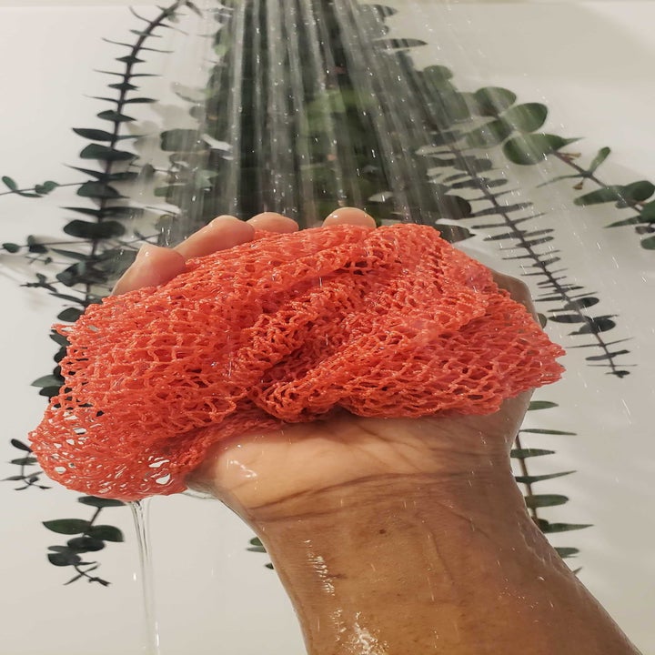 Marquaysa's hand holding the cloth in the shower with the water running.
