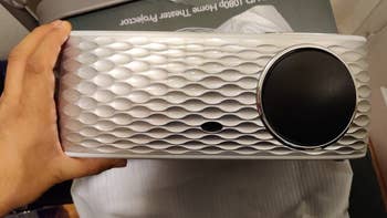 a reviewer holding the silver and white projector