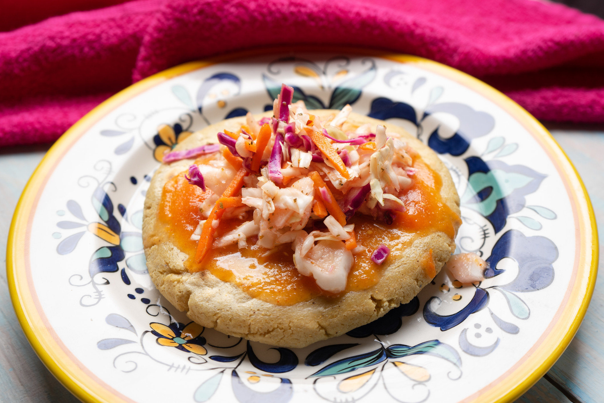 A plate containing a Salvadorian pupusa with pickled cabbage.