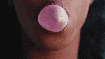 Janelle Monáe blowing a bubble with her gum