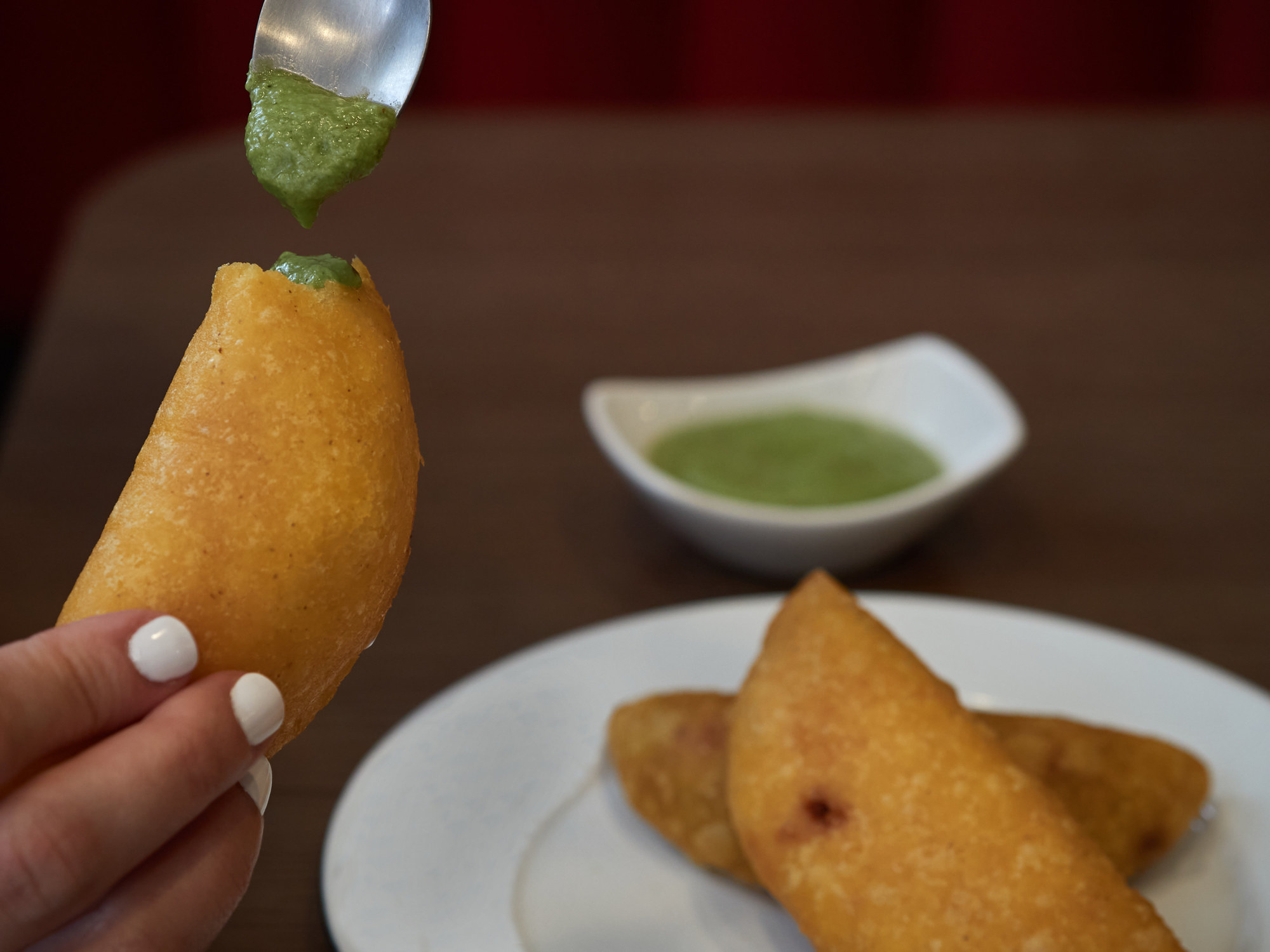 Empanadas topped with a spoonful guasacaca.