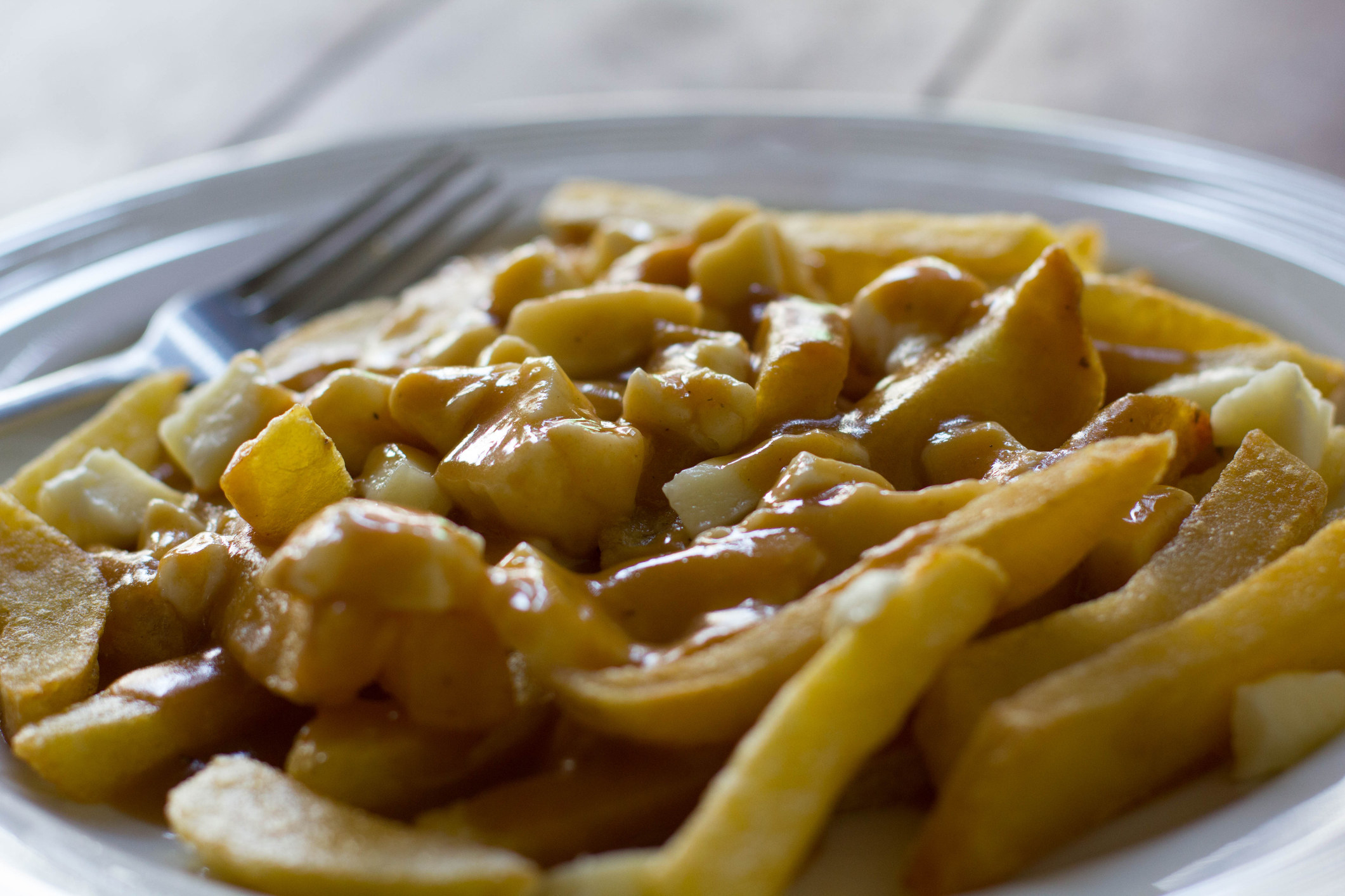 A plate of poutine with gravy and cheese curds.