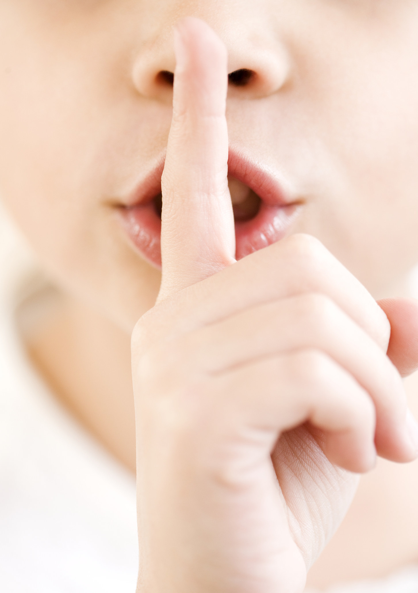 Close up of a young girl with her finger on her lips saying &quot;ssh&quot;