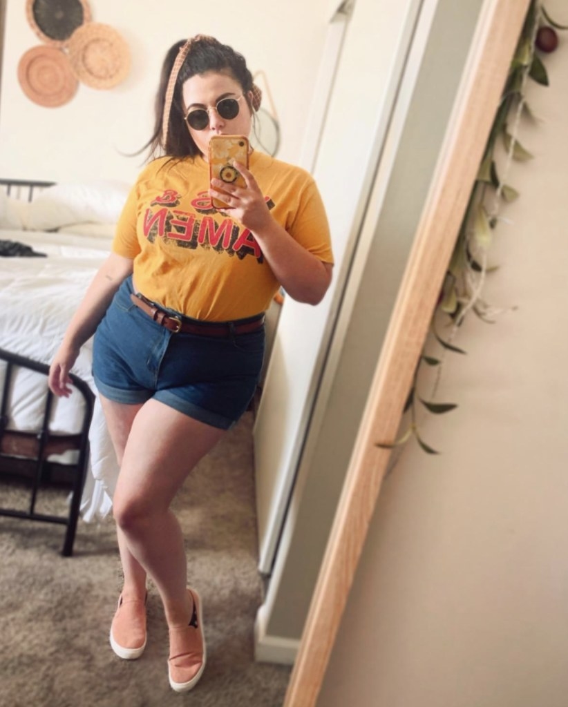 A reviewer wearing a yellow top and denim shorts