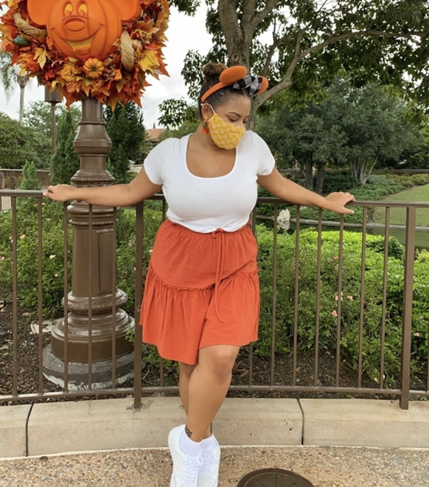 A person wearing an orange skirt and white top at Disneyland
