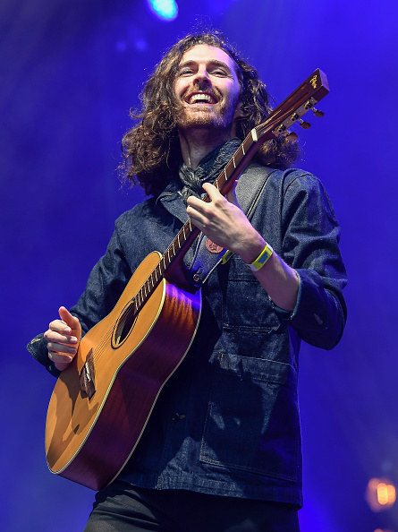 Hozier playing a guitar and smiling