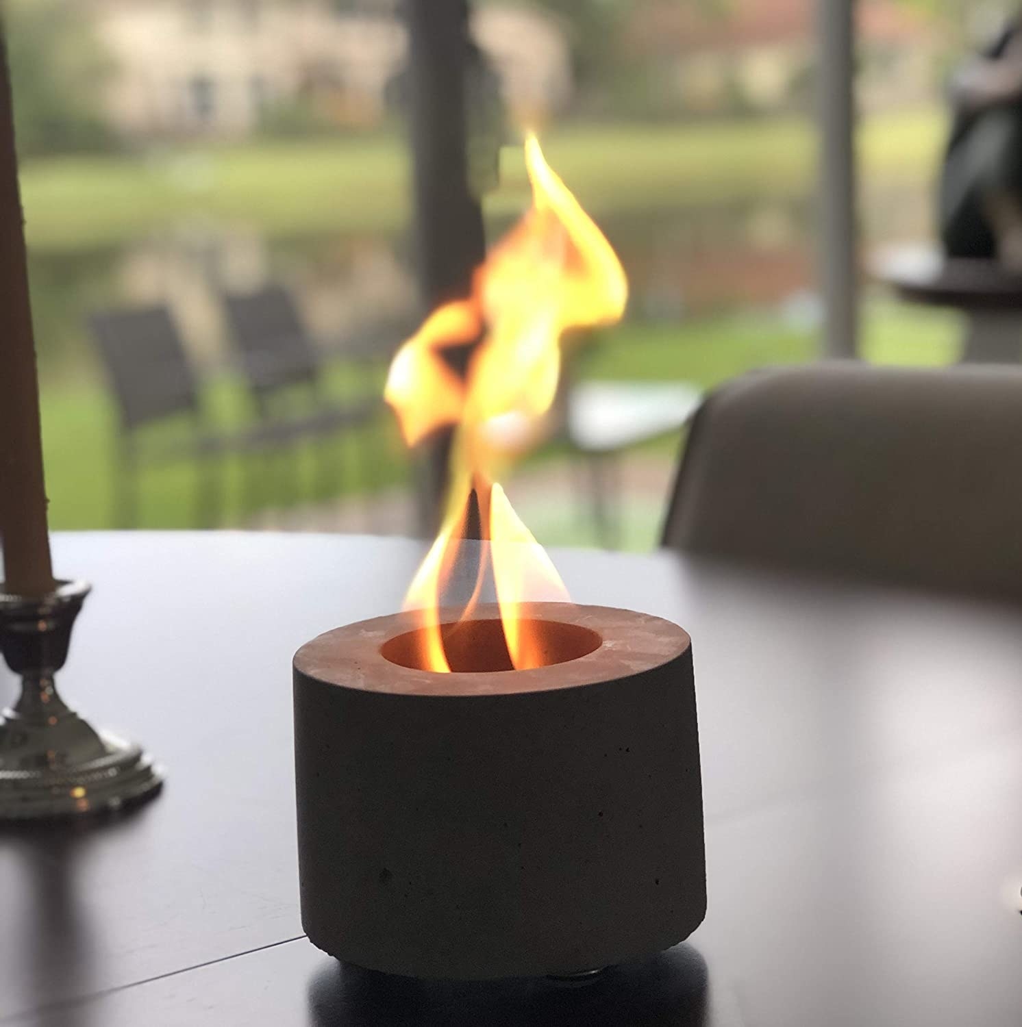 Gray fire pit with lit flame on table outdoors 