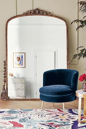 the seven-foot mirror behind a blue velvet chair