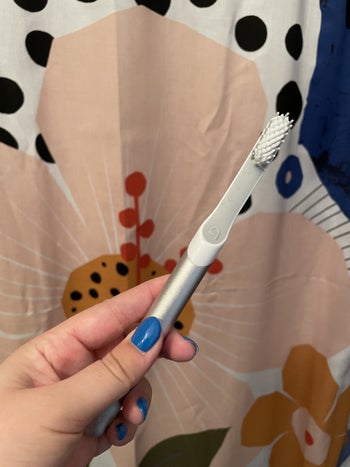 a buzzfeeder holding a silver quip toothbrush