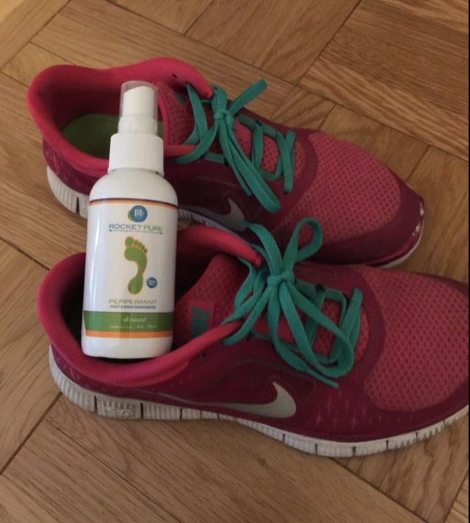 A green, white and orange bottle of spray in a red pair of shoes