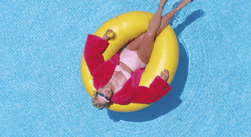 taylor swift floating in a pool with a pink jacket and swimsuit on
