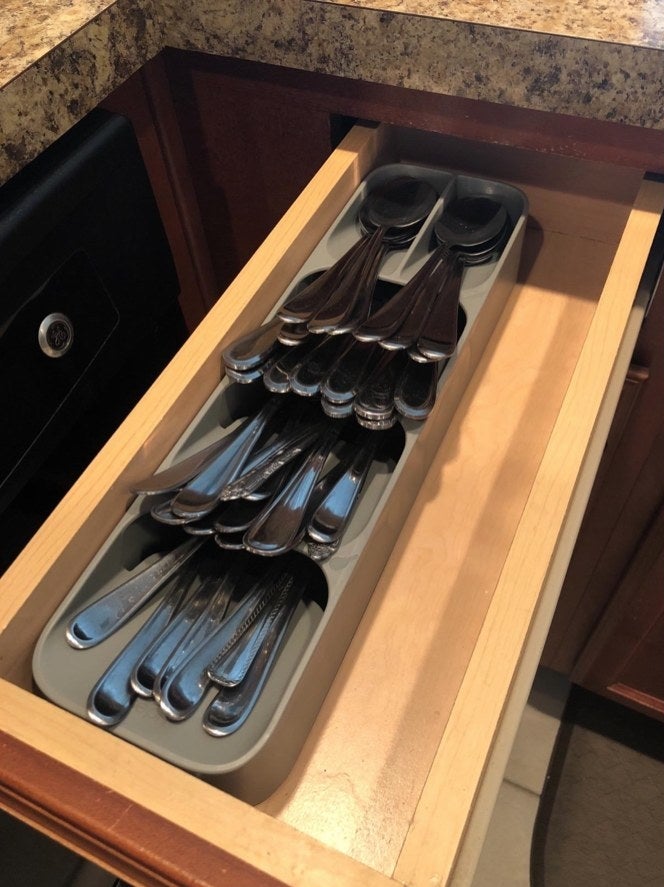 A grey flatware organizer in a drawer