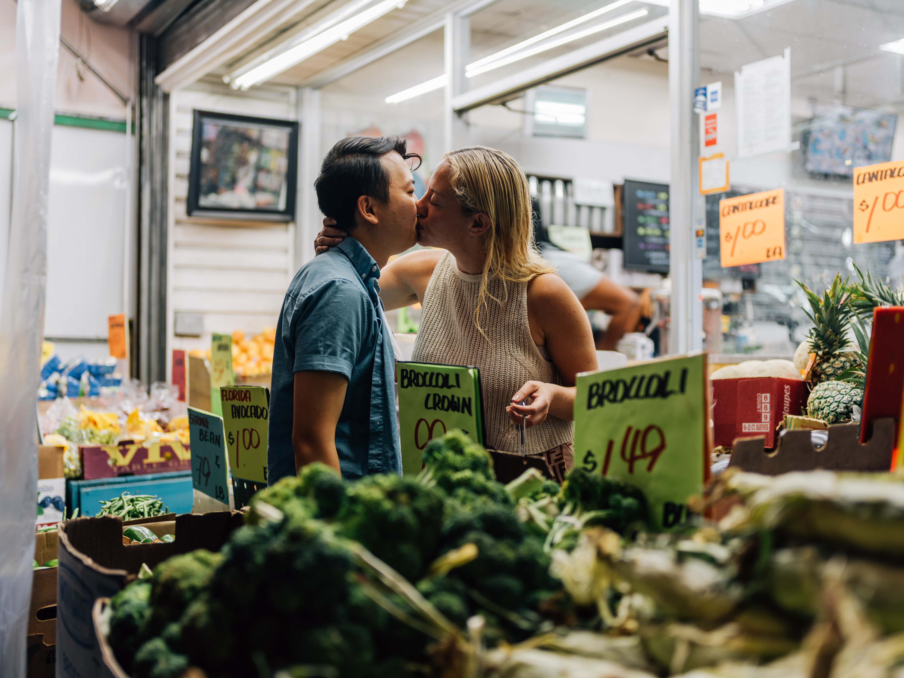 A woman leaning over and kissing the photographer outside a bodega