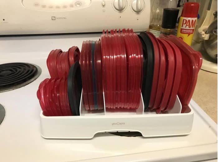A plastic lid organizer with red and black lids in it 