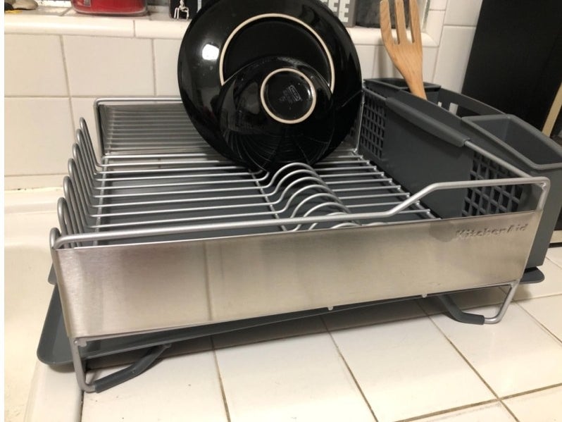 A silver kitchenaid dish rack with black dishes in it