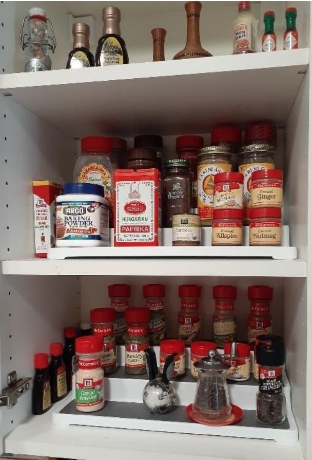 A set of white spice racks holding spice jars in a cabinet