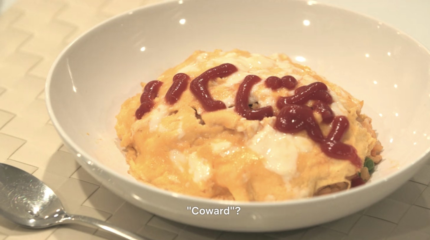 A bow of omurice with coward written in ketchup.