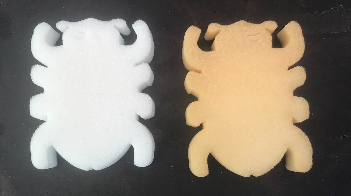 Clean white bug-shaped sponge next to the same shape sponge that's slightly orange