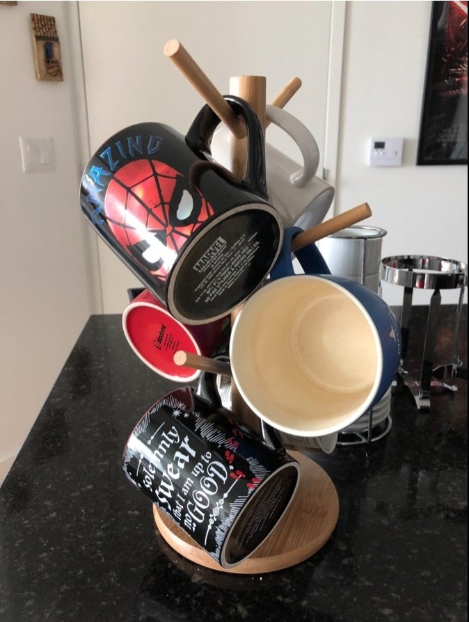 A wooden mug tree covered in colorful mugs