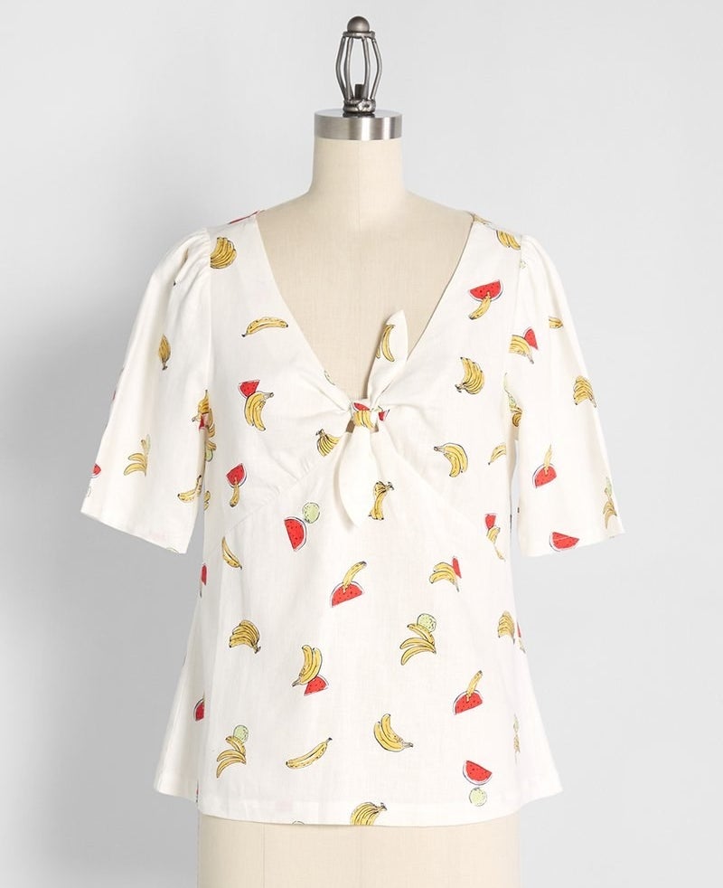 a mannequin wearing a tie-front short sleeve shirt with a V-neckline and a fruit print 