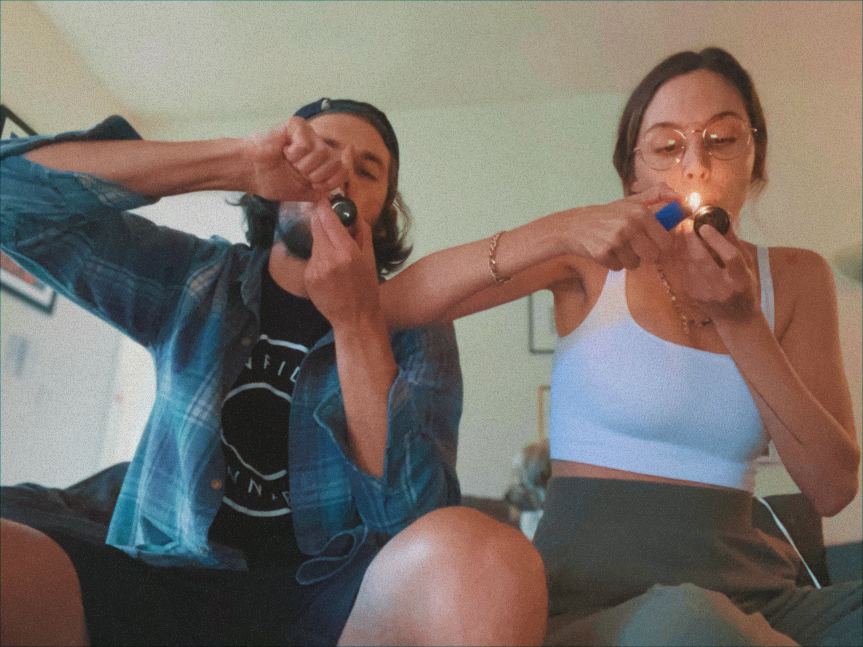 An image of the author&#x27;s boyfriend (left) and the author (right) lighting up pipes to smoke