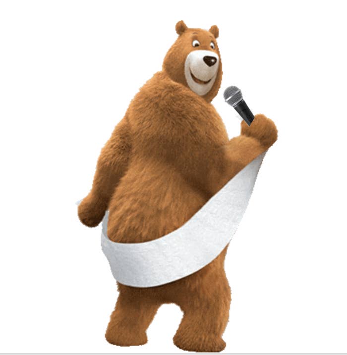 A Charmin bear wrapped in toilet paper with a microphone in their hand