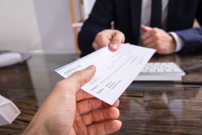 Businessperson giving a cheque to colleague