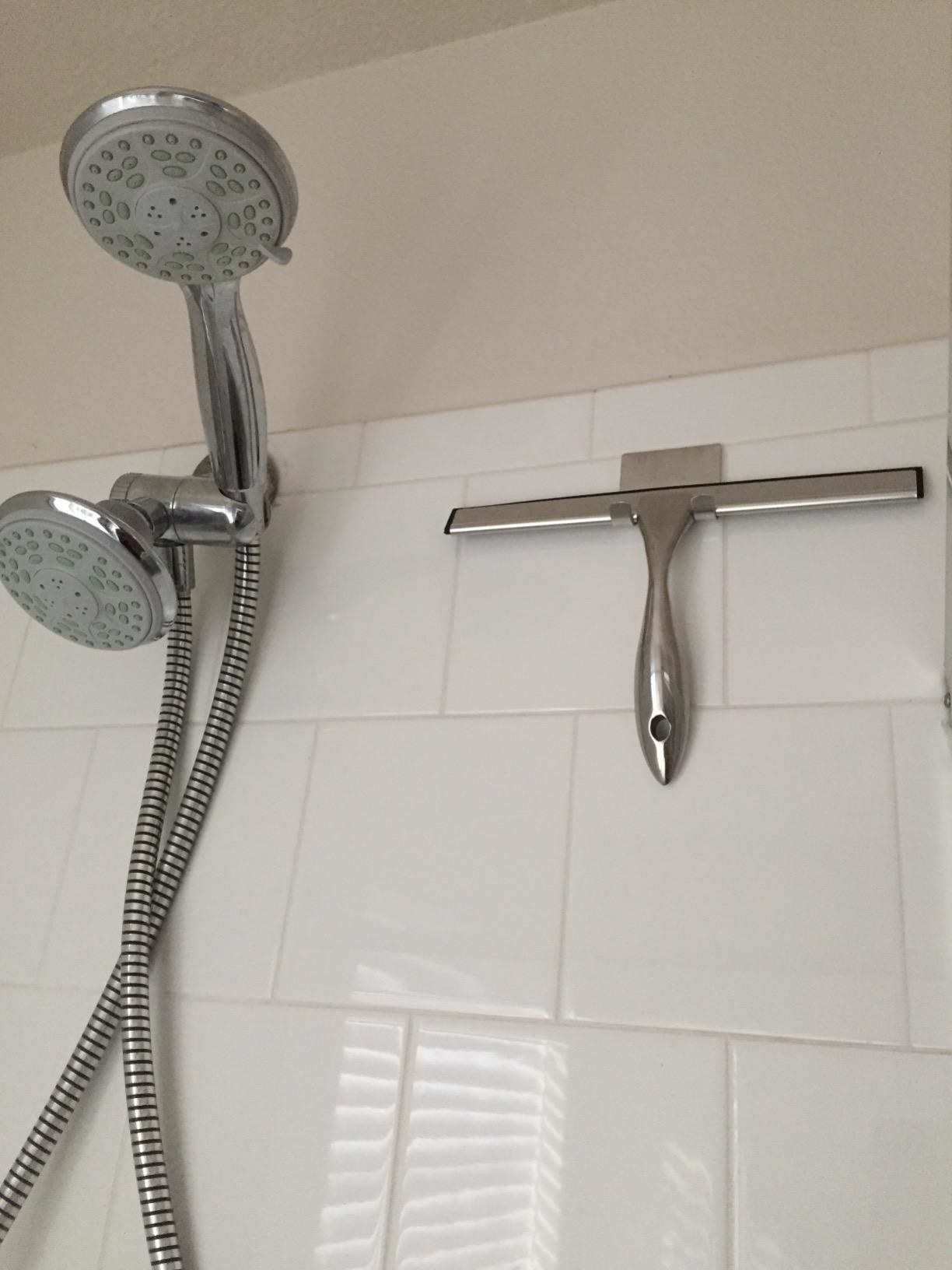 A reviewer photo of the squeegee mounted on its hook in the shower
