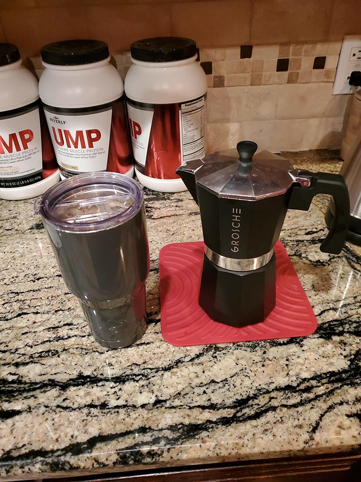 The espresso maker on a counter with a coffee to-go mug