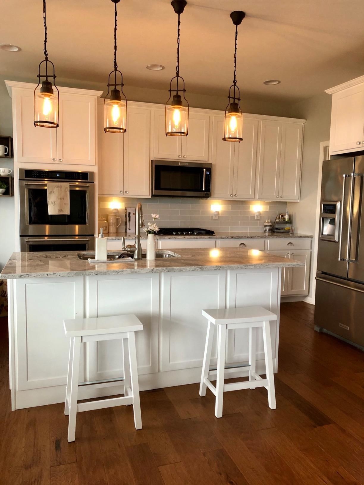 reviewer photo of two backless white wood bar stools next to a counter
